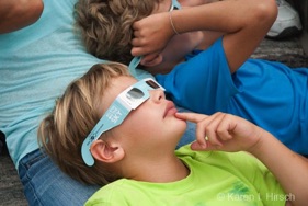 Boy with eclipse glasses looking up